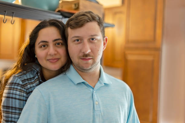 Diverse couple cheek to cheek in their kitchen - fotografia de stock