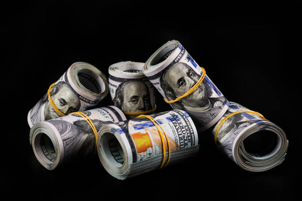 istock Several rolled-up bundles of 100 American dollars bills on a black background 1437597642