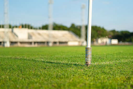 A corner post on the firm ground grass football stadium with the cheering squad stand as blurred background.