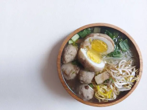egg meatballs. completed with mustard greens, sprouts, yellow noodles, sound.  served on wooden bowls.  savory taste.  isolated background in white.