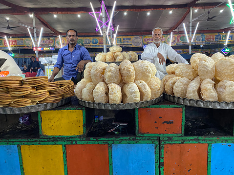 Delhi, India - September 6, 2022: Stock photo showing close-up view of street food vendors selling trays of snacks from a food stall in under cover market.
