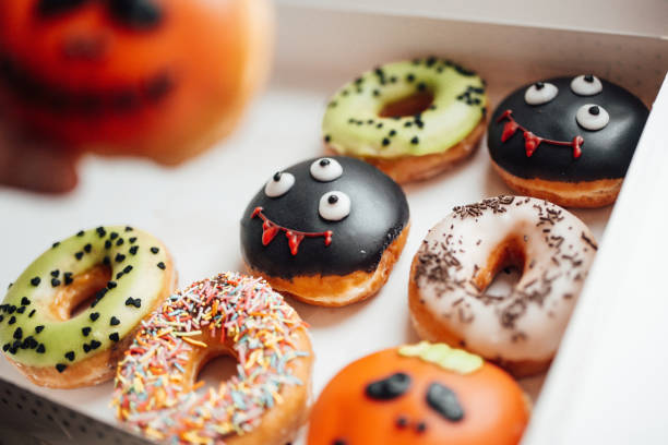 istock Assortment of halloween monsters with funny faces donuts in box at home interior 1437626434