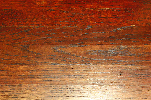 A top view of a wooden laminate flooring with scratches under the lights
