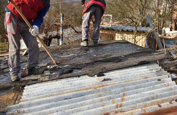 Roof workers remove pieces of cardboard roof manually with shovel stock photo