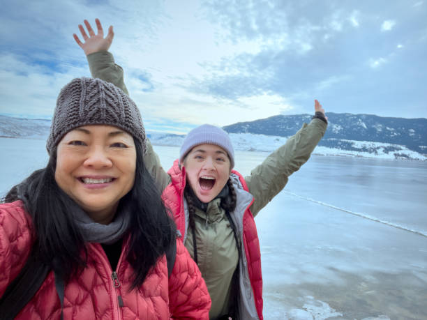Reife asiatische Mutter, eurasische erwachsene Tochter Selfie, Winter gefroren Seeufer – Foto