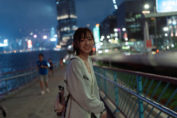 istock Young Asian woman looking back smiling while enjoying the night view outdoors with city lights and skyscrapers on the street 1437635312