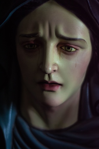 A closeup shot of a statue of a crying and sad woman