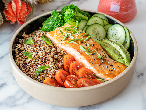 A plate of salmon with quinoa and raw vegetables