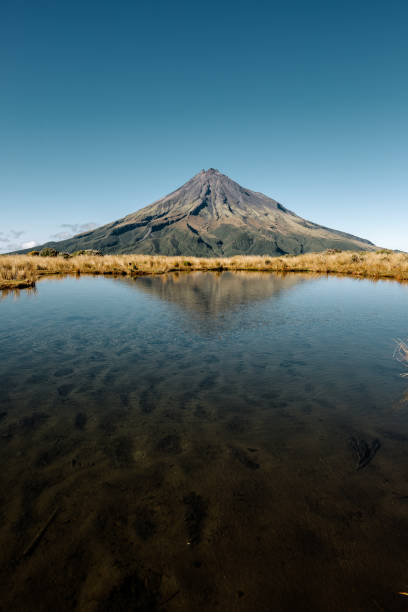 vertikale aufnahme eines hohen mount taranaki in der nähe des sees, egmont national park north new zealand - new zealand landscape taranaki mountain stock-fotos und bilder