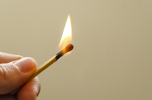 A closeup shot of a person holding a burning matchstick