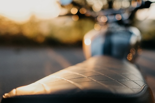 A shallow focus closeup shot of a motorcycle seat during the sunset