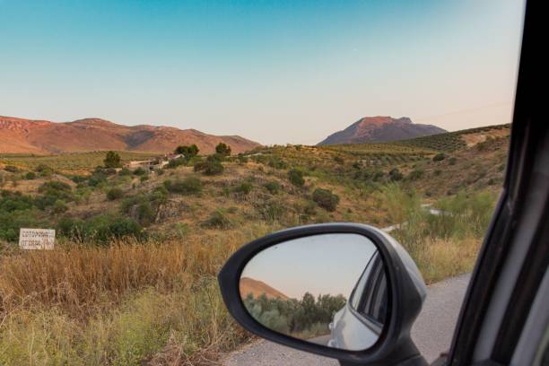 istock Driver's POV from a side mirror of a rural landscape with grass fields and hills 1437642797