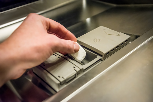 A closeup shot of a man putting detergent tablet Into dishwasher