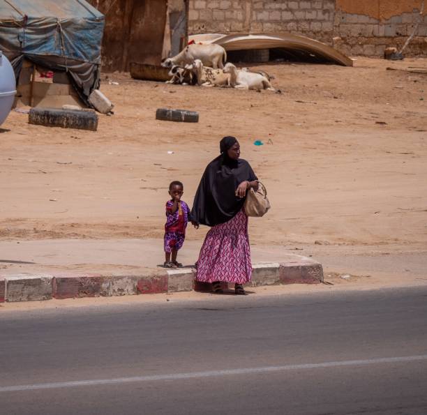 une femme avec un enfant traverse la rue - mauritania photos et images de collection