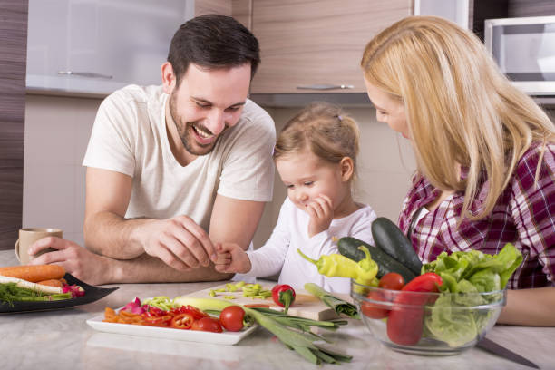 istock Happy family having fun in the kitchen while preparing fresh vegetable salad 1437646211