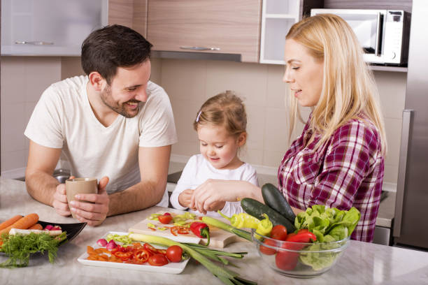 istock Happy family making a salad with fresh vegetables on the kitchen counter 1437646340