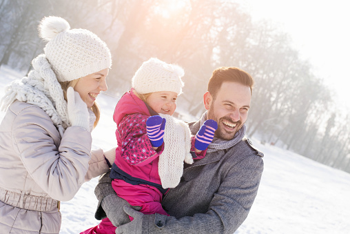A happy family and their little daughter enjoying a beautiful and cold winter day
