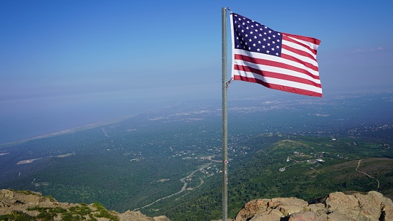 A view of the USA flag on the background of a sea and green land