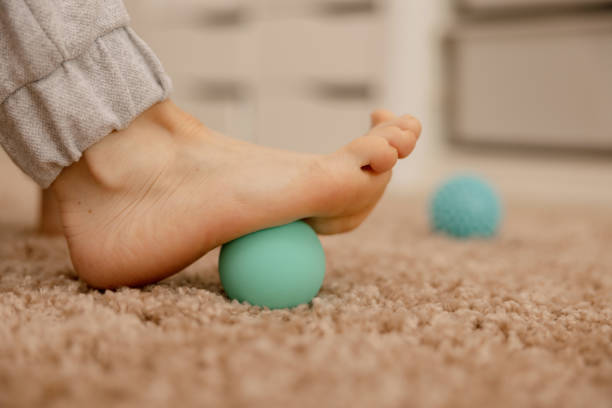 Woman doing flatfoot correction gymnastic exercise using massage ball. Myofascial relaxation of foot muscles. Hallux valgus. Pain. Identification of flat feet. Self care practices at home, healthcare mujer haciendo ejercicio gimnástico de corrección de pie plano usando pelota de masaje. relajación miofascial de los músculos del pie. hallux valgus. dolor. identificación de pies planos. prácticas de autocuidado en el hogar, atención médica.