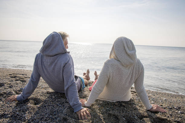 They wear hoodies and look out to sea