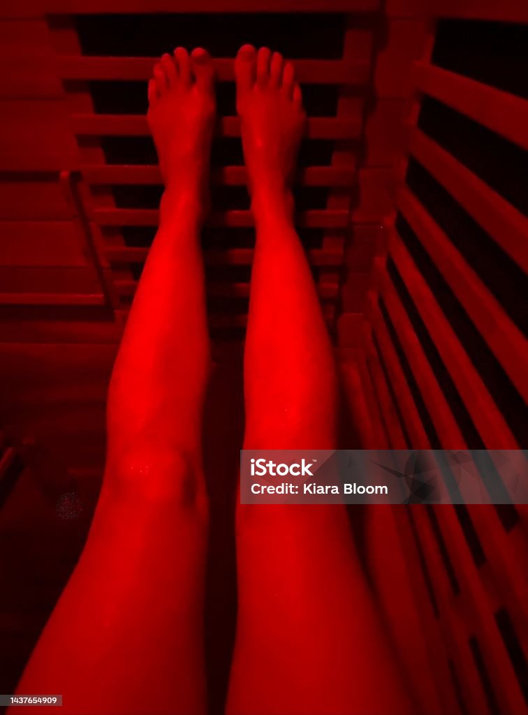 Infrared Sauna Vertical looking down to legs with feet up in infrared sauna with wood surrounds and red color light therapy Infrared Stock Photo