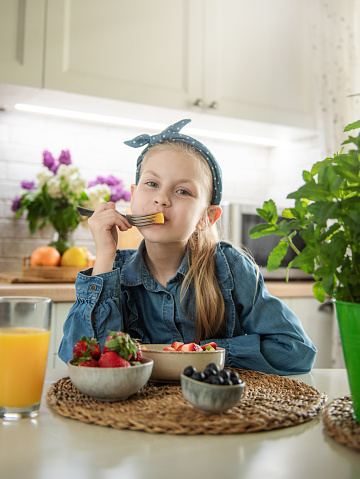 Healthy food at home. Cute little girl eats fruit salad