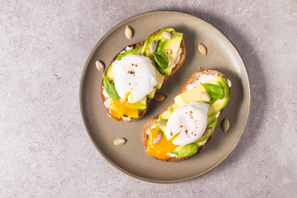 istock Toast with avocado, soft cream cheese, rye bread and poached Egg. Wholemeal open sandwich for healthy breakfast concept. 1437661141
