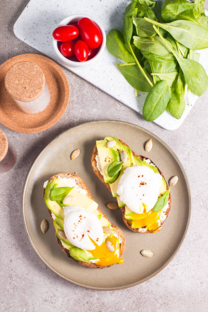 istock Toast with avocado, soft cream cheese, rye bread and poached Egg. Wholemeal open sandwich for healthy breakfast concept. 1437661143