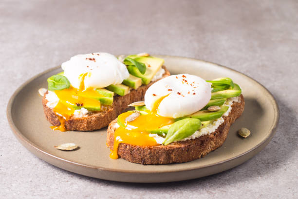 istock Toast with avocado, soft cream cheese, rye bread and poached Egg. Wholemeal open sandwich for healthy breakfast concept. 1437661144