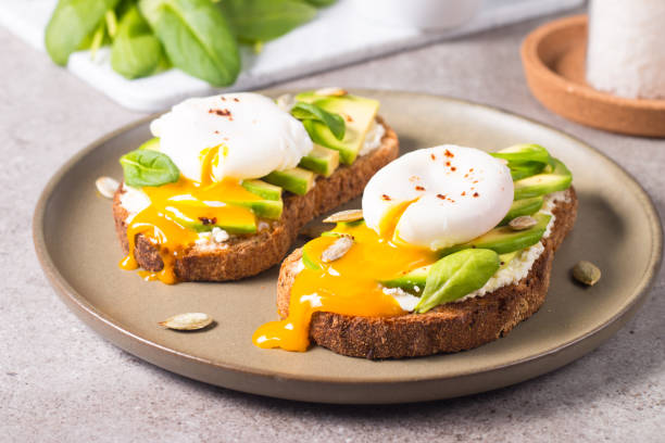 istock Toast with avocado, soft cream cheese, rye bread and poached Egg. Wholemeal open sandwich for healthy breakfast concept. 1437661154