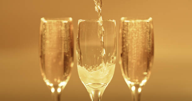 champagne, verres en cristal et boisson au vin mousseux pour une célébration, un événement de luxe ou une fête. boissons alcoolisées, liquides dorés et boissons alcoolisées versés dans un verre à boire et toasts festifs - champagne champagne flute pouring wine photos et images de collection