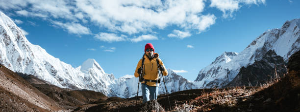 istock Professional expeditor with trekking sticks and traveling backpack going by mountains tack. Solo tourist hiking across high snowy mountain 1437664400