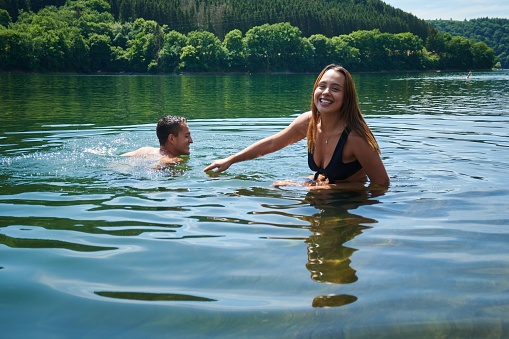 A happy couple swimming in the water on the background of forest