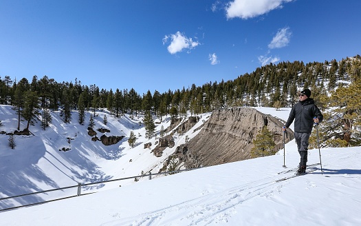 Mammoth Lakes, California, United States – February 17, 2018: A cross country skiier passes by the Inyo Craters, a natural crater feature in the mountains near the winter destination of Mammoth Lakes.