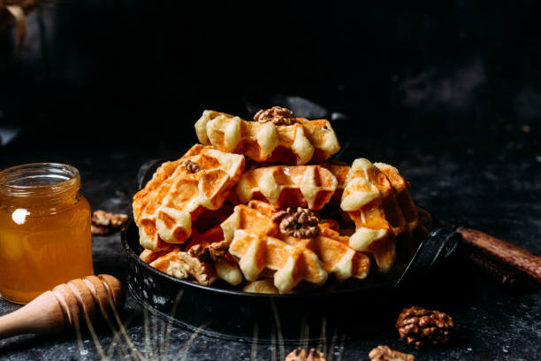 istock Belgian waffles with honey and nuts on a dark background 1437668328