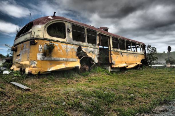 istock Old abandoned wrecked bus in a field against the dark cloudy sky 1437668445