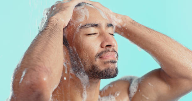 homem, chuveiro e lavagem de pelos da cabeça na rotina de limpeza, bem-estar saudável e autocuidado pela manhã. zoom, rosto e sabão xampu para modelo em fundo azul em relaxar cuidados com o cabelo do banheiro com água de limpeza - shower human face men wet - fotografias e filmes do acervo