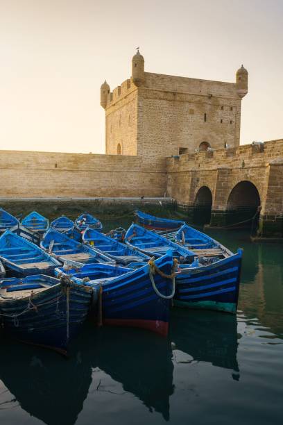 scatto verticale di barche blu anatre nel porto di essaouira skala du port con un grazioso skyline - essaouira foto e immagini stock