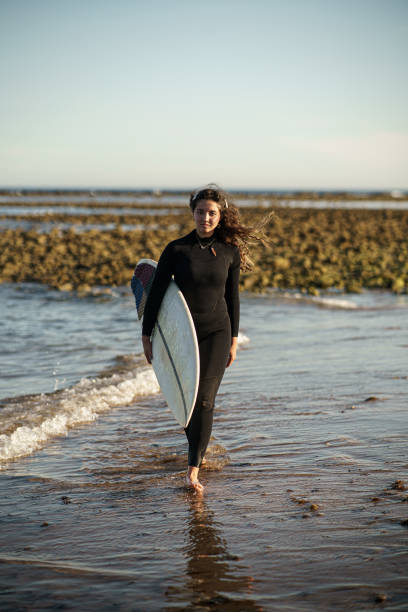 istock Young beautiful surfer female on the beach at sunset 1437669075