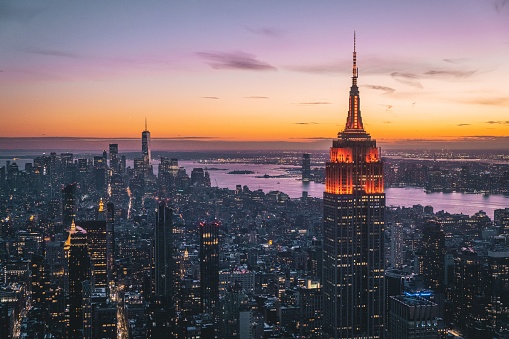 A bird's eye view of skyscrapers and Empire State Building illuminated at sunset in New York, USA