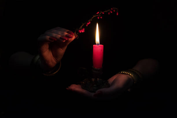 Women's hands  with bracelets and rings holding a burning candle in the dark. stock photo