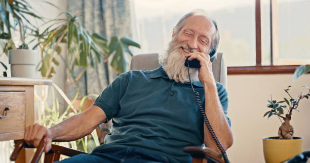 aposentadoria, idoso e homem em telefone fixo desfrutando de comunicação casual na austrália casa. pensão, idosos e homens maduros na poltrona em conversa feliz e amigável por telefone. - telefone fixo - fotografias e filmes do acervo