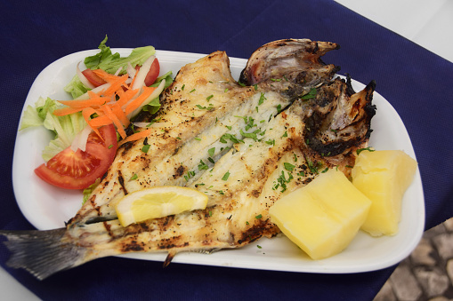 Traditionally prepared Portuguese grilled whole sea bass or Robalo served with boiled potatoes and a side salad.