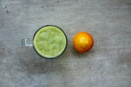 Healthy smoothies and muffin on a concrete table.