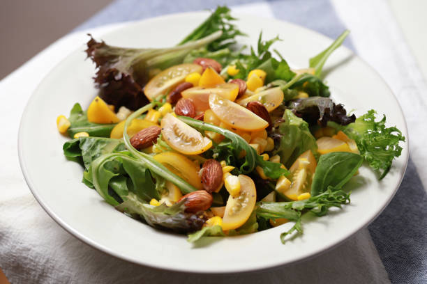 A multi-coloured healthy salad bowl with assorted fresh fruits and vegetables, lettuce, tomatoes, rocket and corn close-up