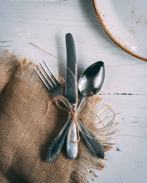 istock Fork, knife, and spoon tied in a bow on the wooden table 1437678490