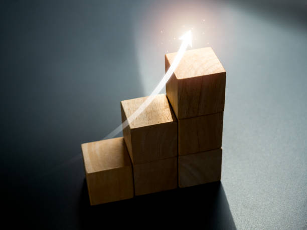Shining rise up arrow on wooden cube blocks, bar graph chart steps on dark background, business growth process, grow marketing, technology trend, economic improvement concepts, minimal style. flecha ascendente brillante en bloques de cubo de madera, pasos de gráfico de barras sobre fondo oscuro, proceso de crecimiento empresarial, marketing de crecimiento, tendencia tecnológica, conceptos de mejora económica, estilo minimalista.
