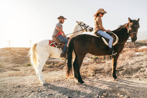 Young couple riding horses doing excursion at sunset - Focus on woman face stock photo