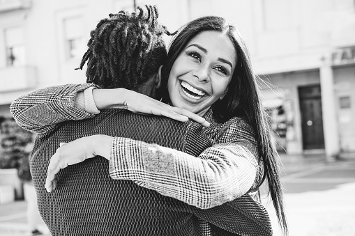 Happy african couple having fun hugging outdoor in the city - Focus on girl face - Black and white editing