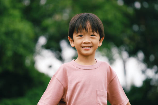 A close up of a young boy smiling at the park. stock photo